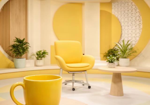 Ochtendshow met presentator en koffiemok in gele studio